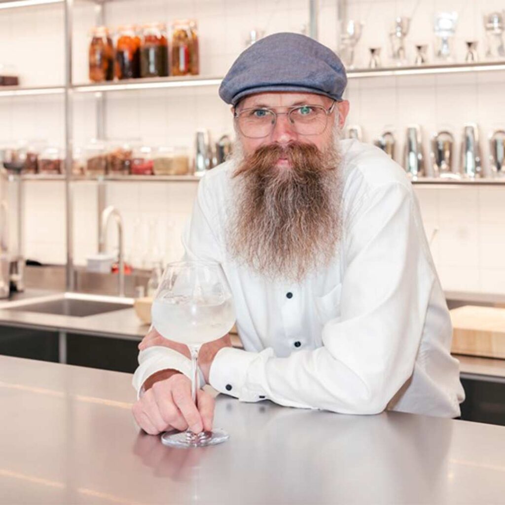 Jens Josefsson från GinSweden lutar sig mot en bardisk med ett kupaglas Gin & Tonic