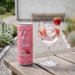Skånska Spritfabriken Alkoholfri G & Tonic Rosé Strawberry 330 ml burk bredvid ett drinkglas med is och jordgubbar