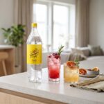 schweppes-indian-tonic-drink-inspiration En flaska Schweppes Indian Tonic 1,5L på en köksbänk bredvid två färgglada drinkar med is och garnering.